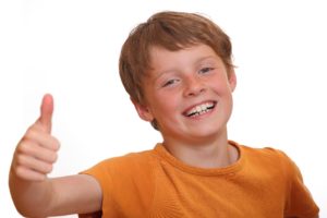 A smiling young boy shows thumbs up